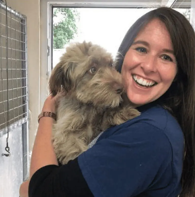 Photo of Paws2Rescue team member Laura smiling while holding a small dog